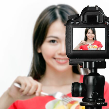 Asian food vlogger with fruit salad behind camera, social media production concept