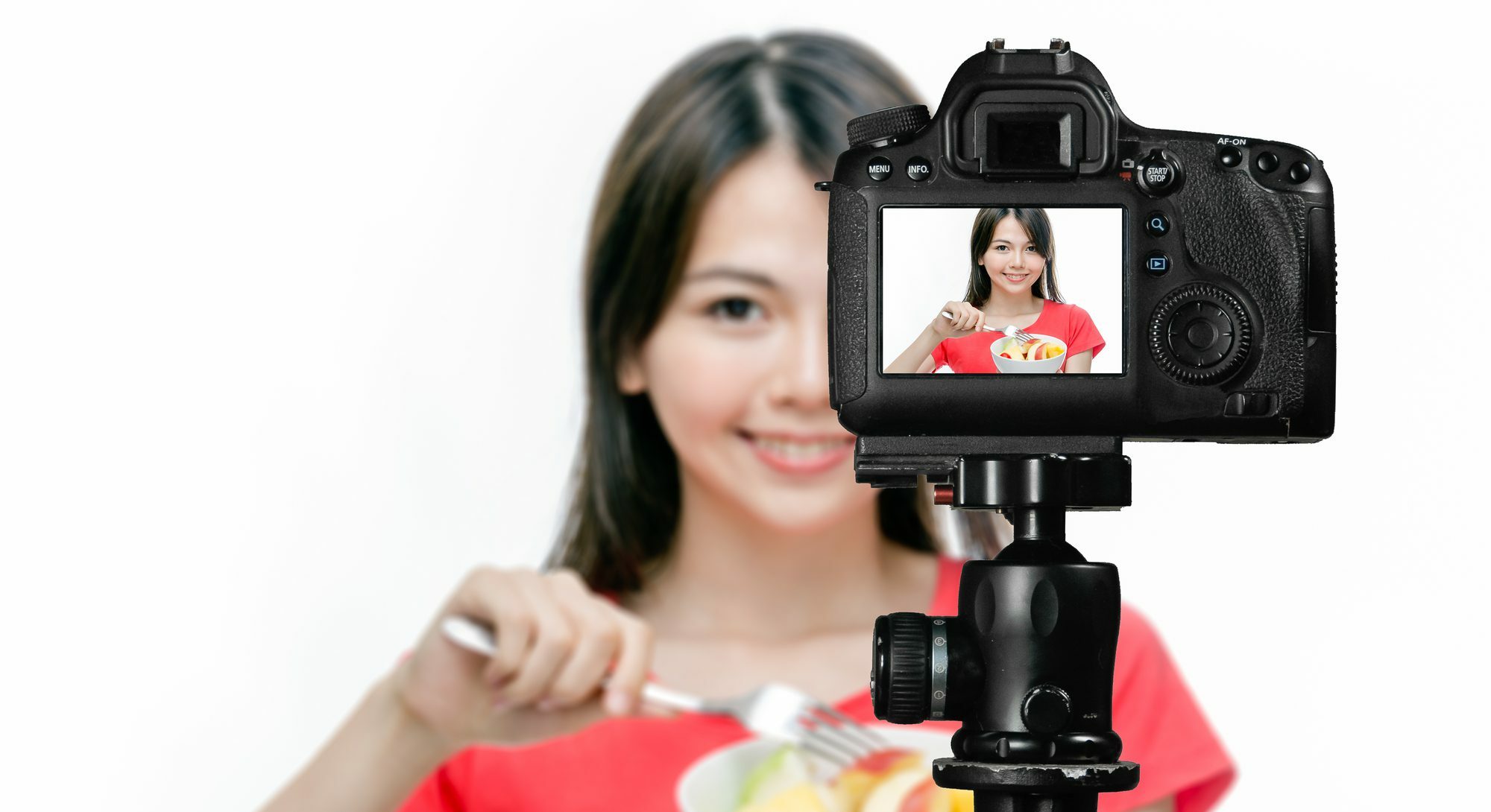 Asian food vlogger with fruit salad behind camera, social media production concept