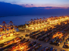Container ship in export and import business and logistics. Shipping cargo to harbor by crane. Water transport International. Aerial view