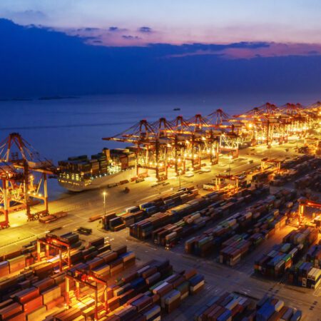 Container ship in export and import business and logistics. Shipping cargo to harbor by crane. Water transport International. Aerial view