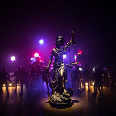 Statue of Justice with anti-riot police helmet holding scale.