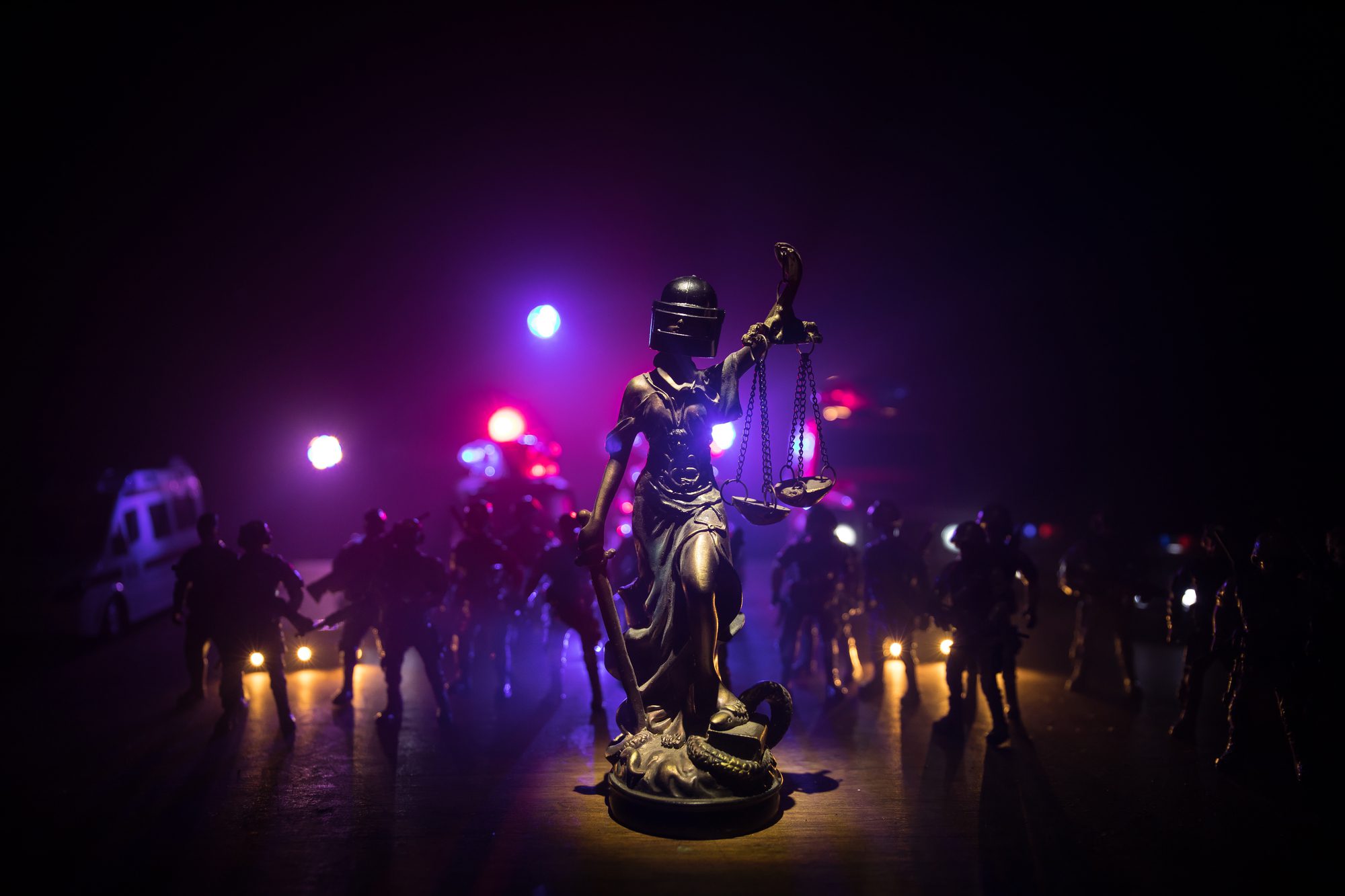 Statue of Justice with anti-riot police helmet holding scale.