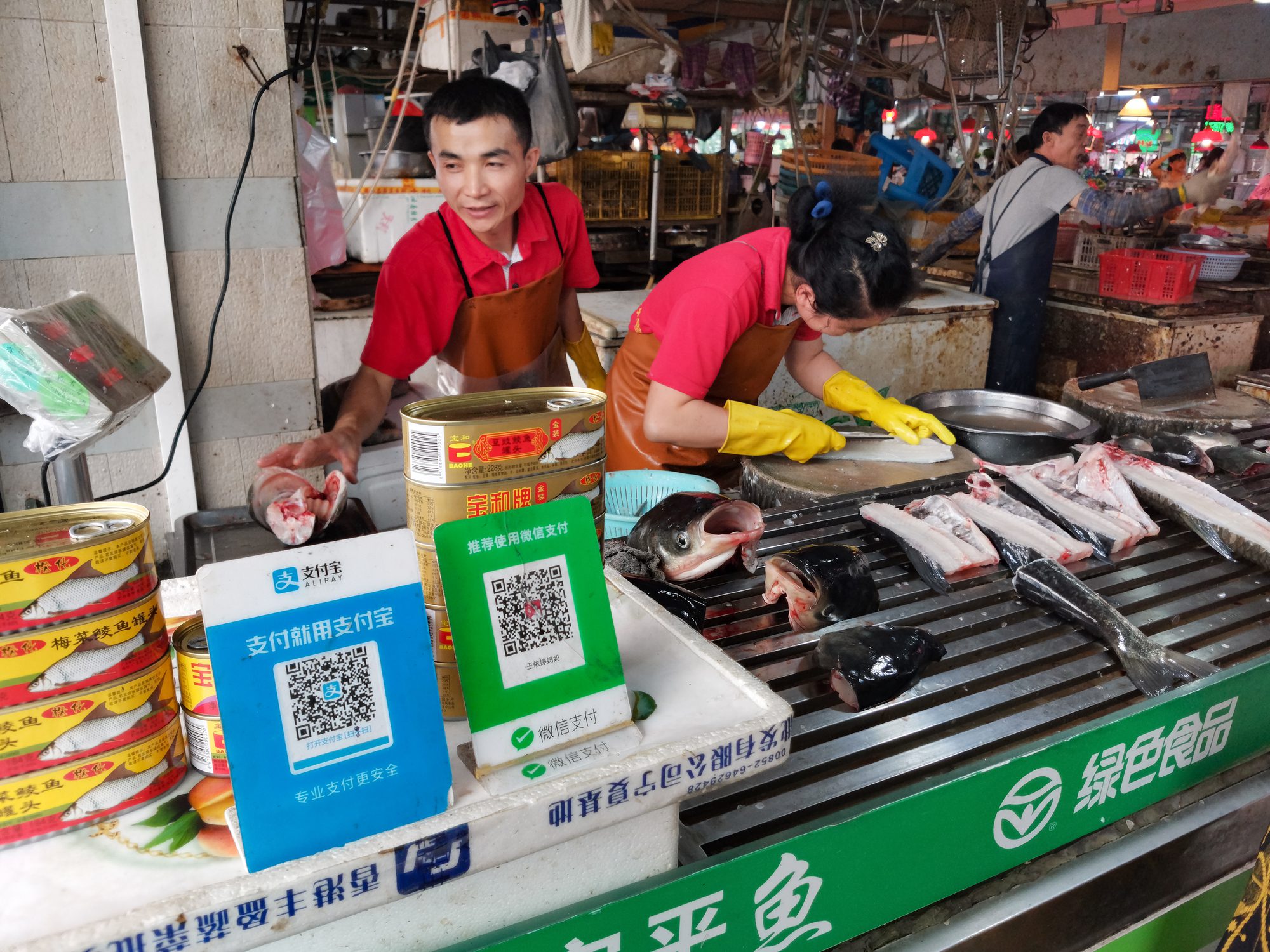 fish retailer in Chinese market with Wechat and Alipay QR codes payment in front.